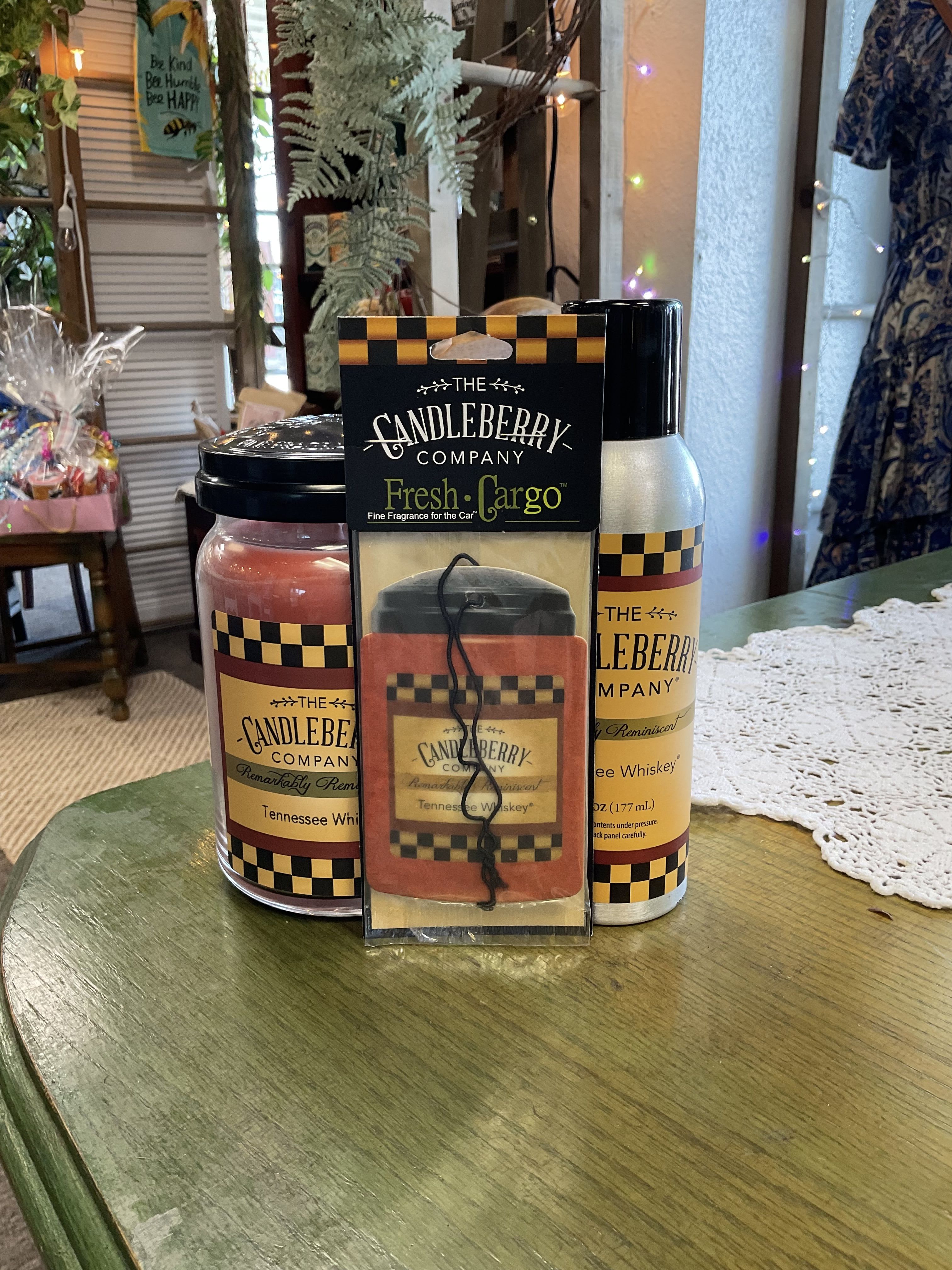 Three Candleberry Company Tennessee Whiskey candles and a car fragrance pack on a table.