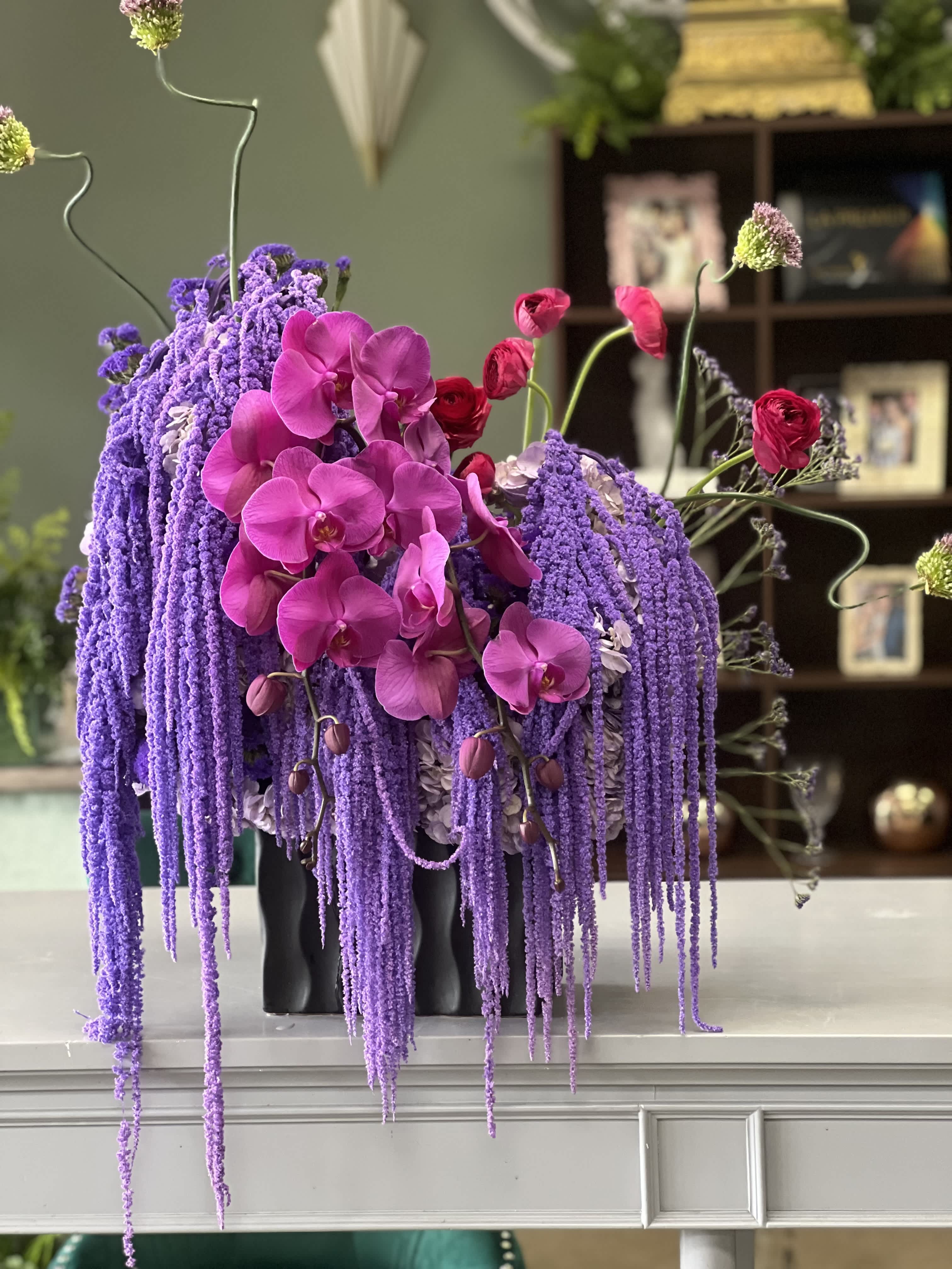 Purple and pink orchid arrangement in a black vase