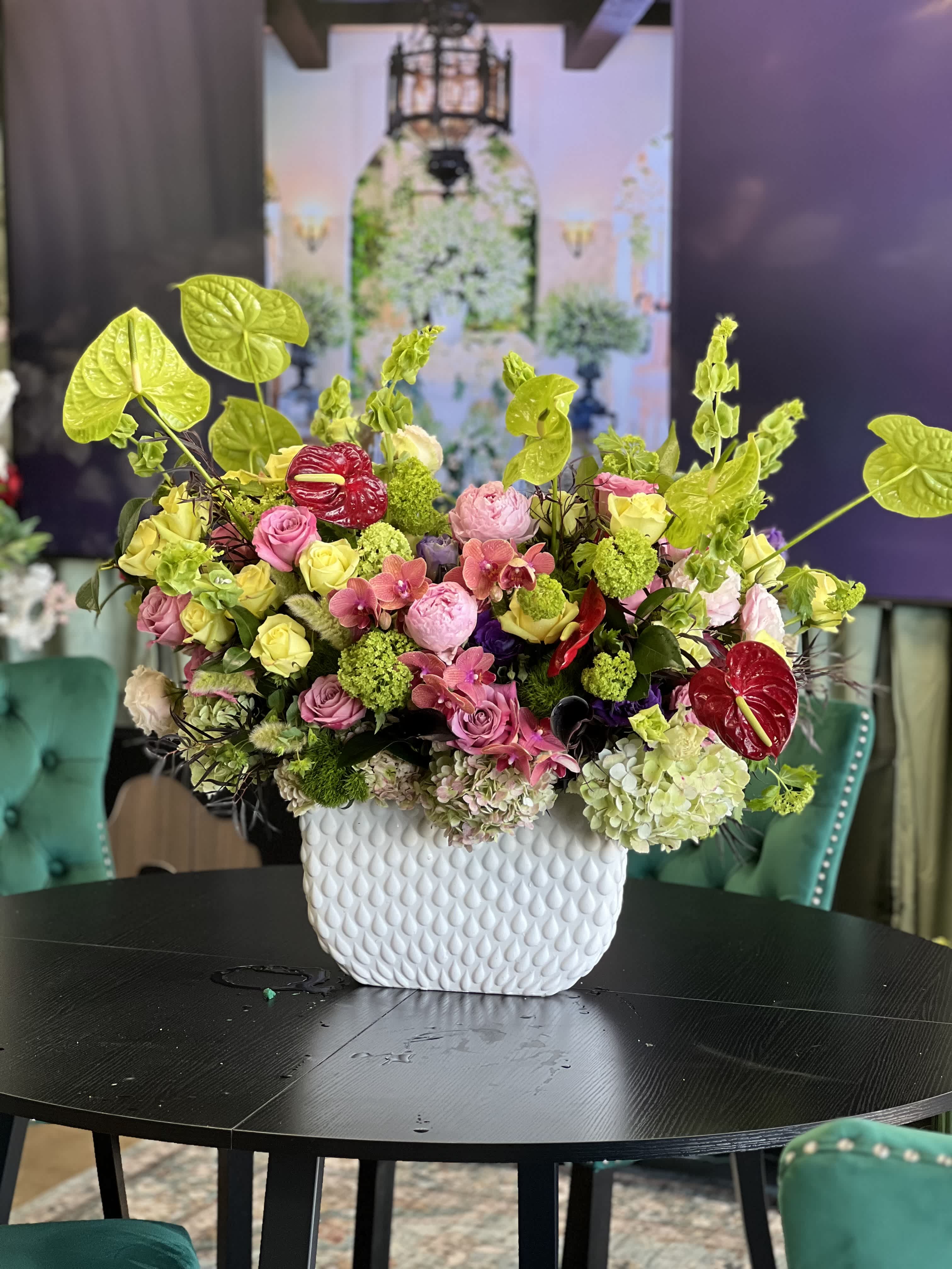 Mixed pink and green floral arrangement in a white textured vase