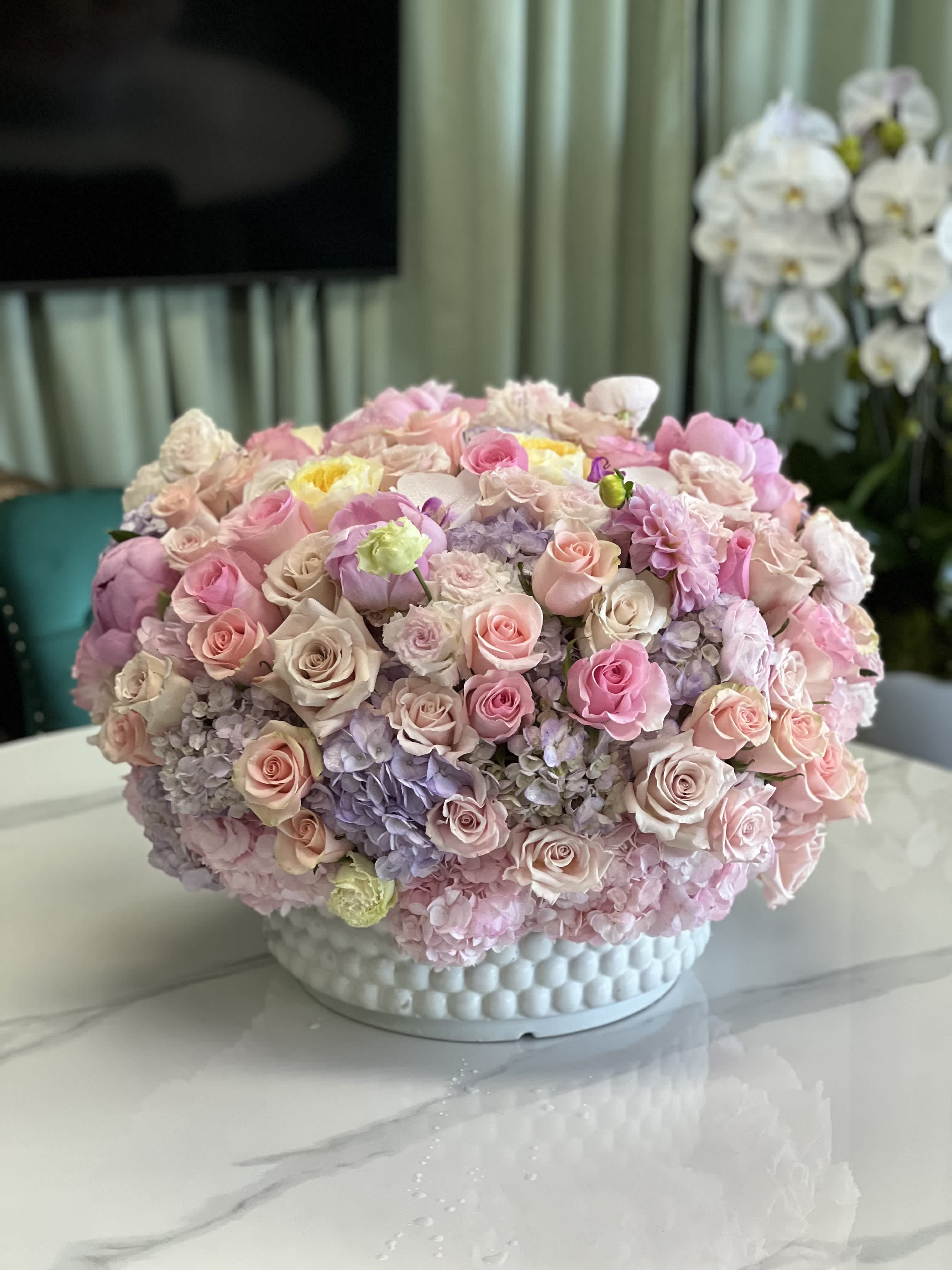 Large pastel bouquet of roses and hydrangeas in a white textured vase