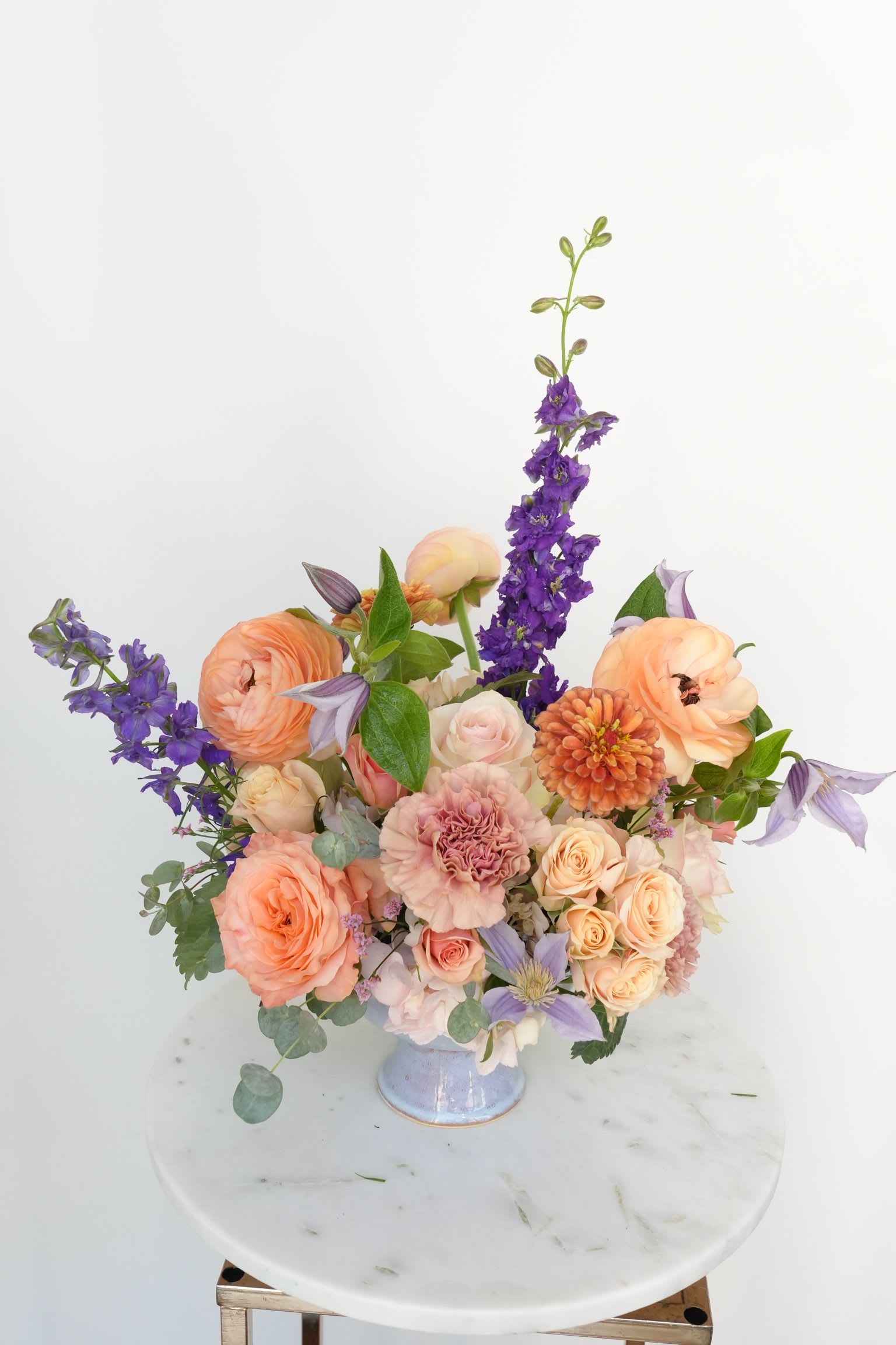 Fall Elegance - Warm neutrals: caramel, honey and golden brown with a touch of deep purple. Ranunculus, roses, dahlia, delphinium.  Arranged in a ceramic vase.