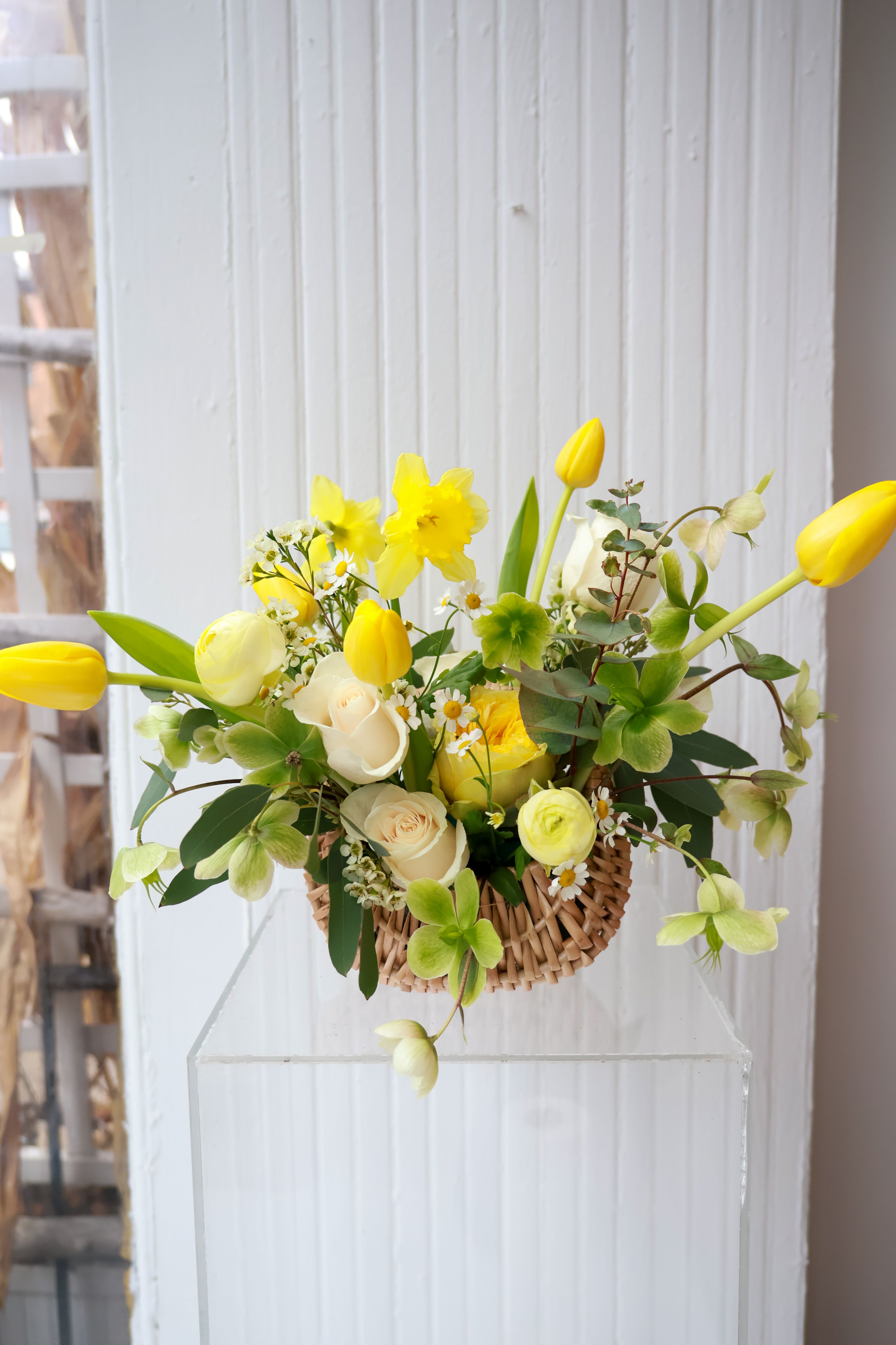 Yellow tulips and white roses in a woven basket arrangement
