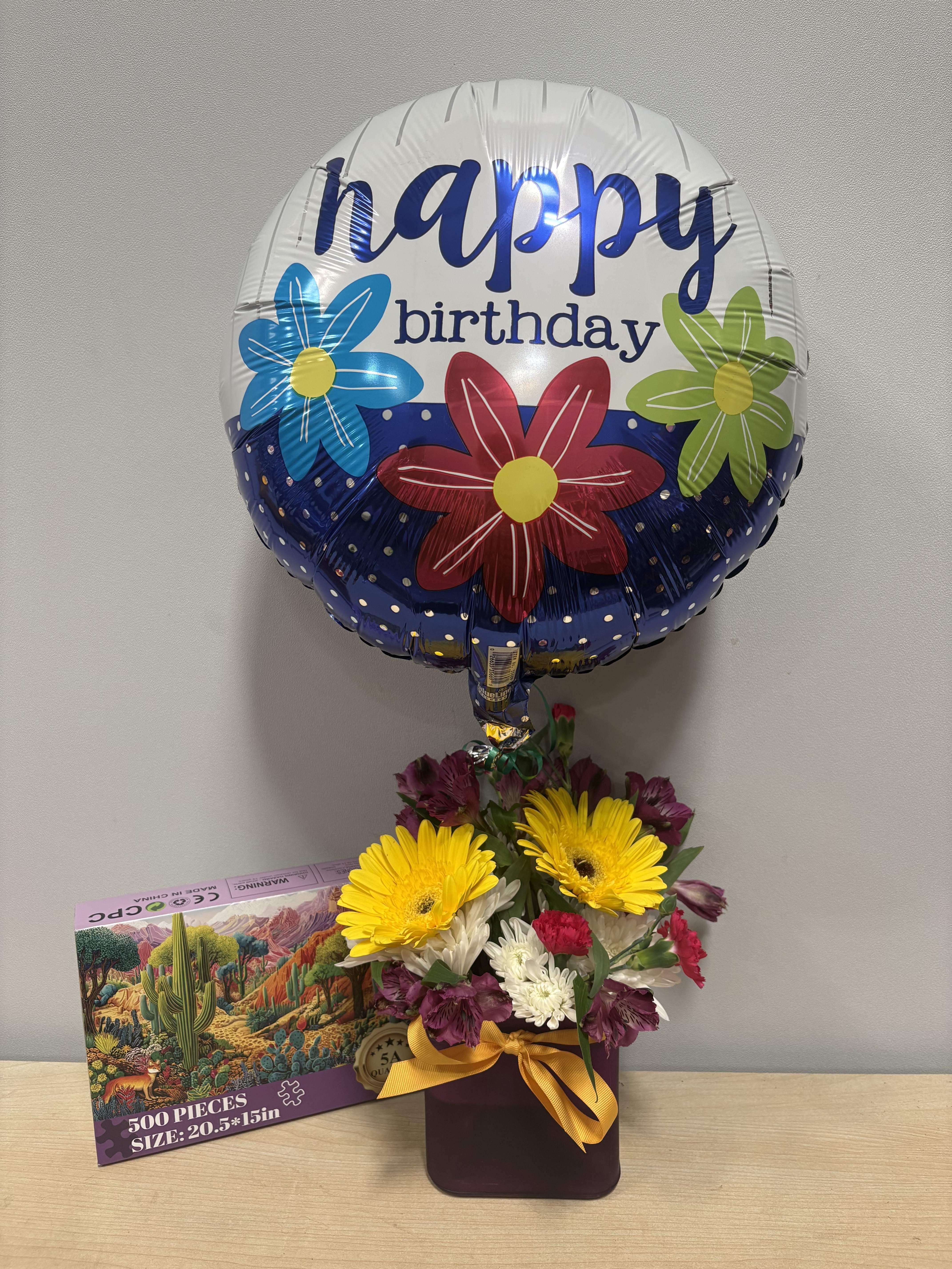 Birthday balloon above a mixed flower arrangement in a vase