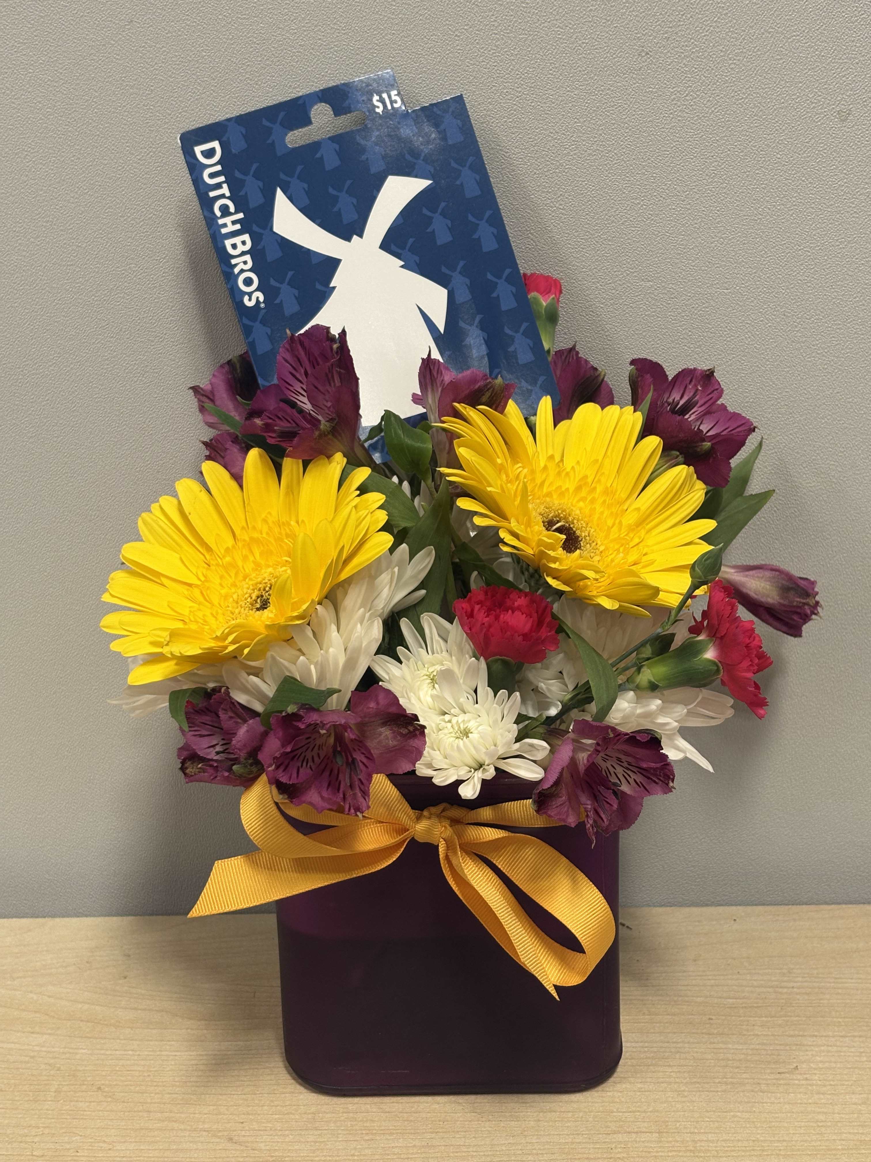 Mixed bouquet in a purple container with a yellow ribbon and Dutch Bros card