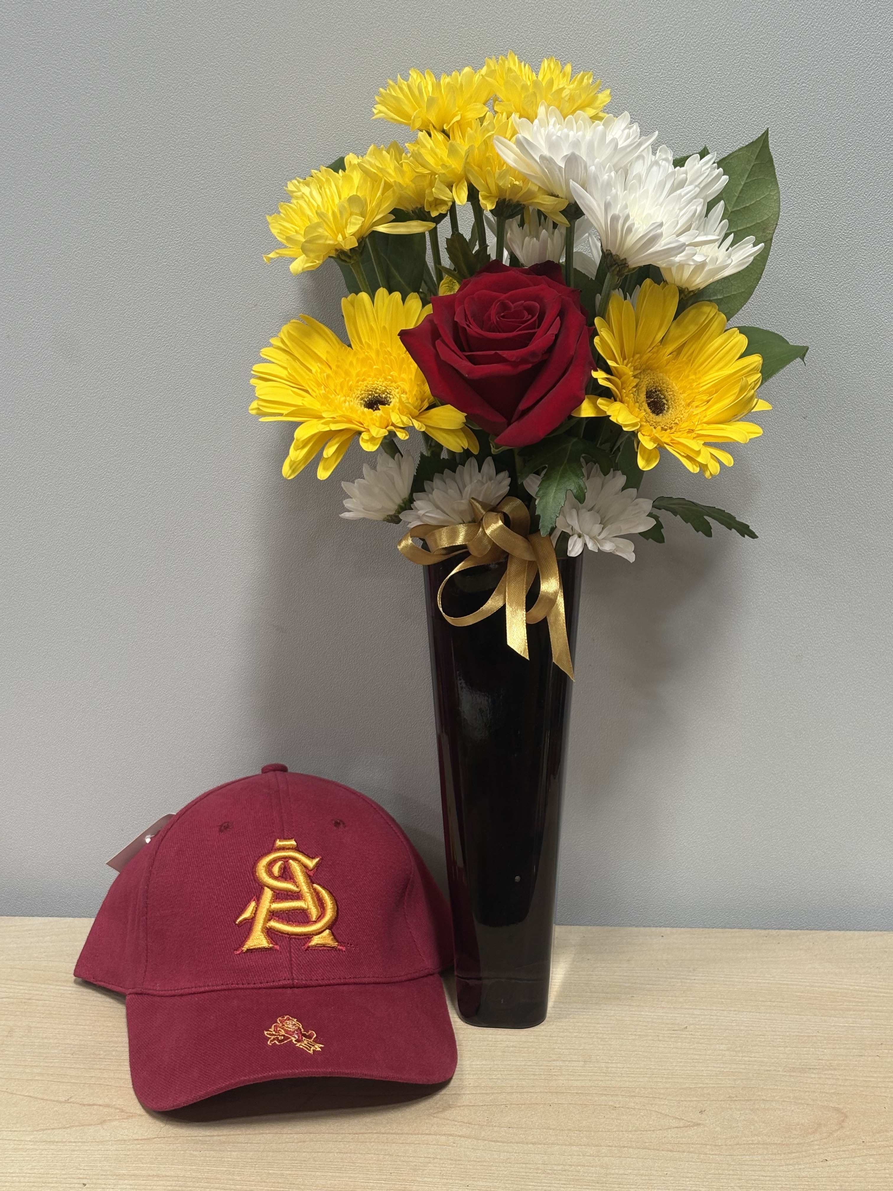 Red rose and yellow-white daisy bouquet in a black vase with a burgundy cap
