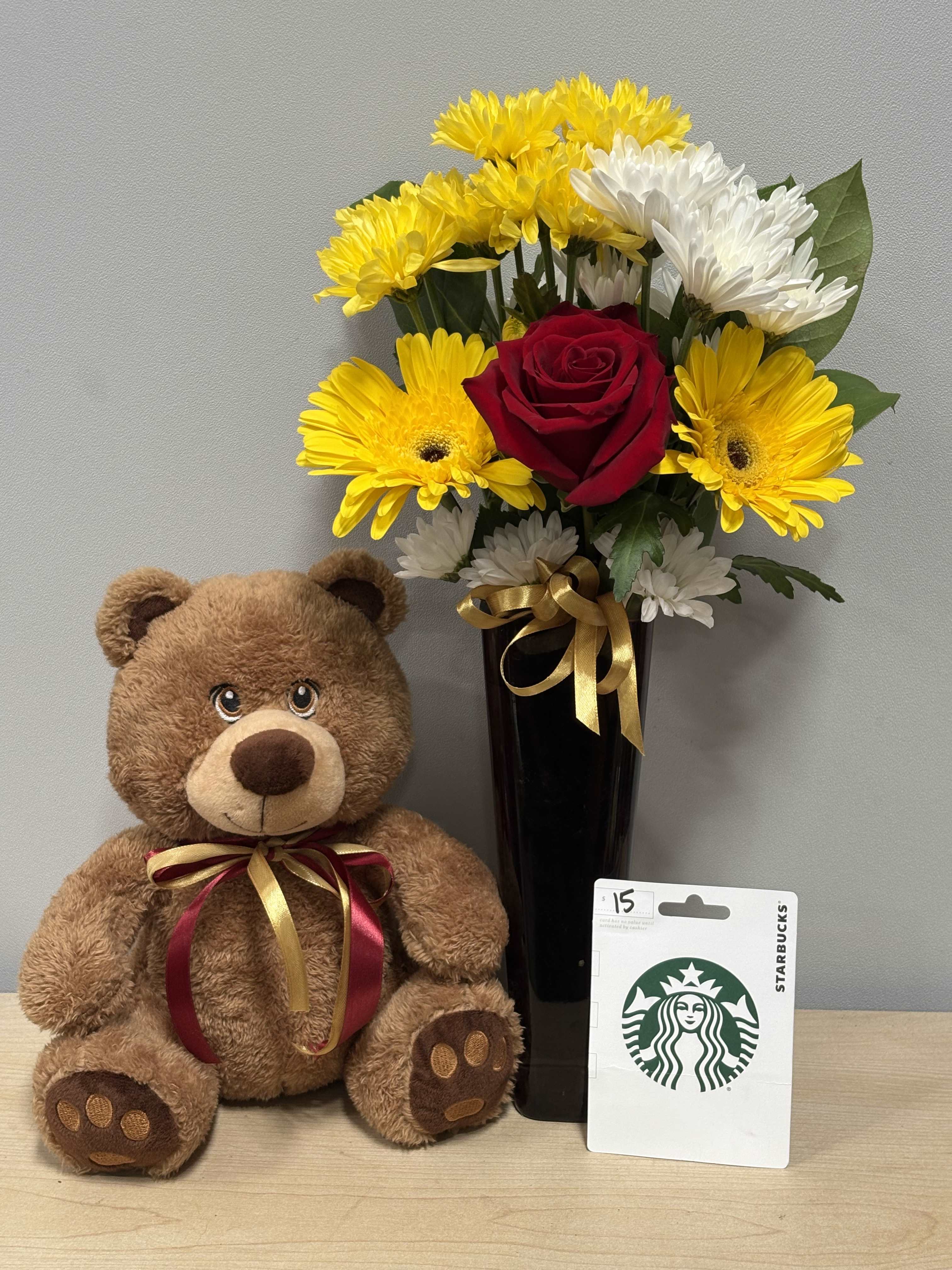 Bouquet of yellow and white flowers in a black vase beside a teddy bear