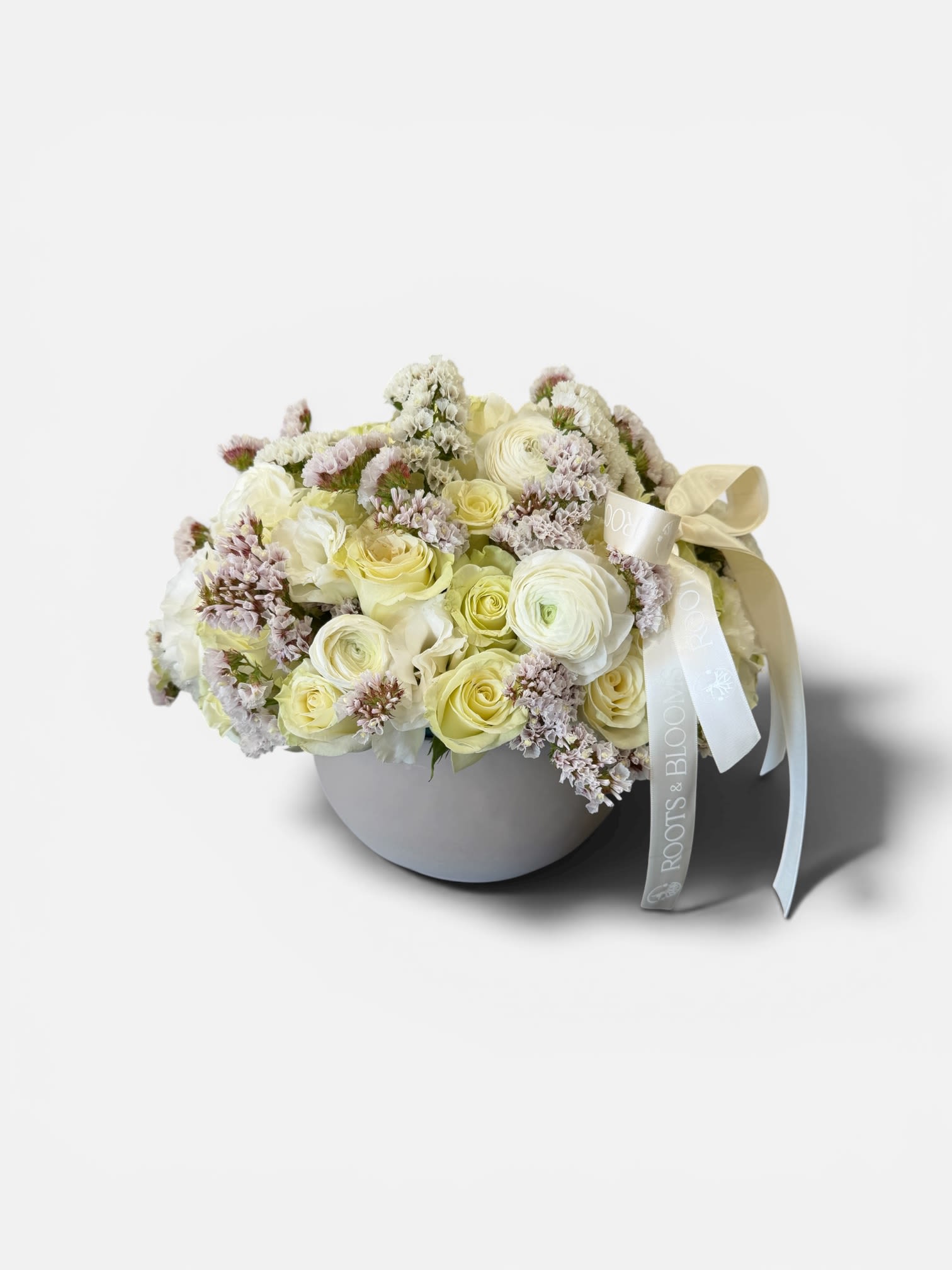 Champagne Garden Luxe - A refined, modern arrangement designed in a sleek ceramic bowl,featuring soft ivory roses, delicate ranunculus, and textured accents of season blooms. This piece blends elegance and simplicity with romantic, airy feel -perfect for sophisticated gifting or adding a touch of luxury to any space.