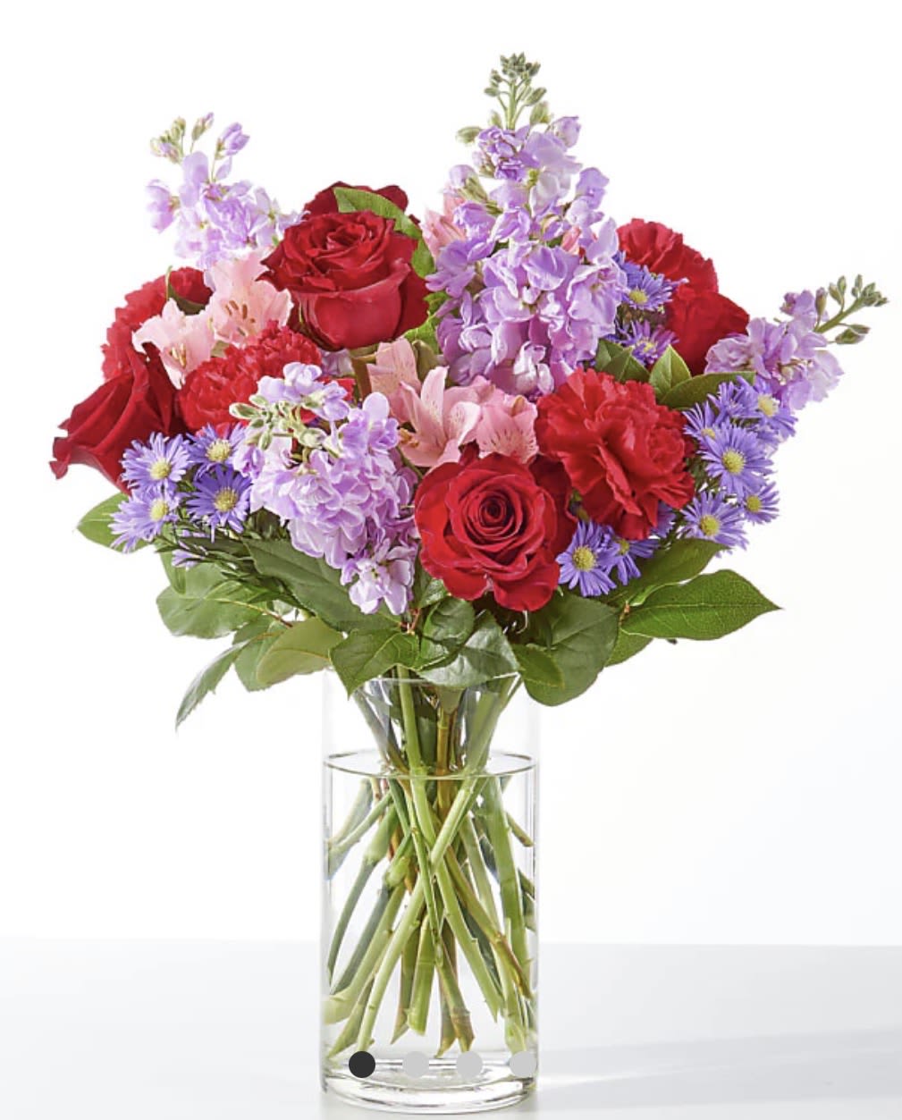 Bouquet of red roses and purple flowers in a clear glass vase