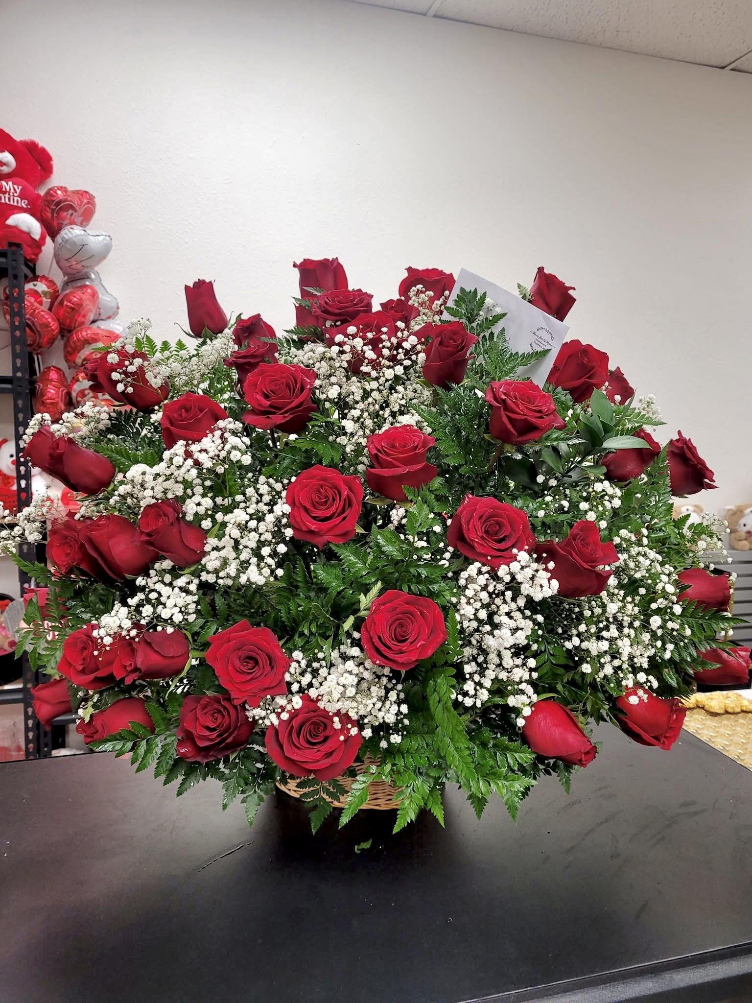 Large bouquet of red roses with white baby's breath in a basket