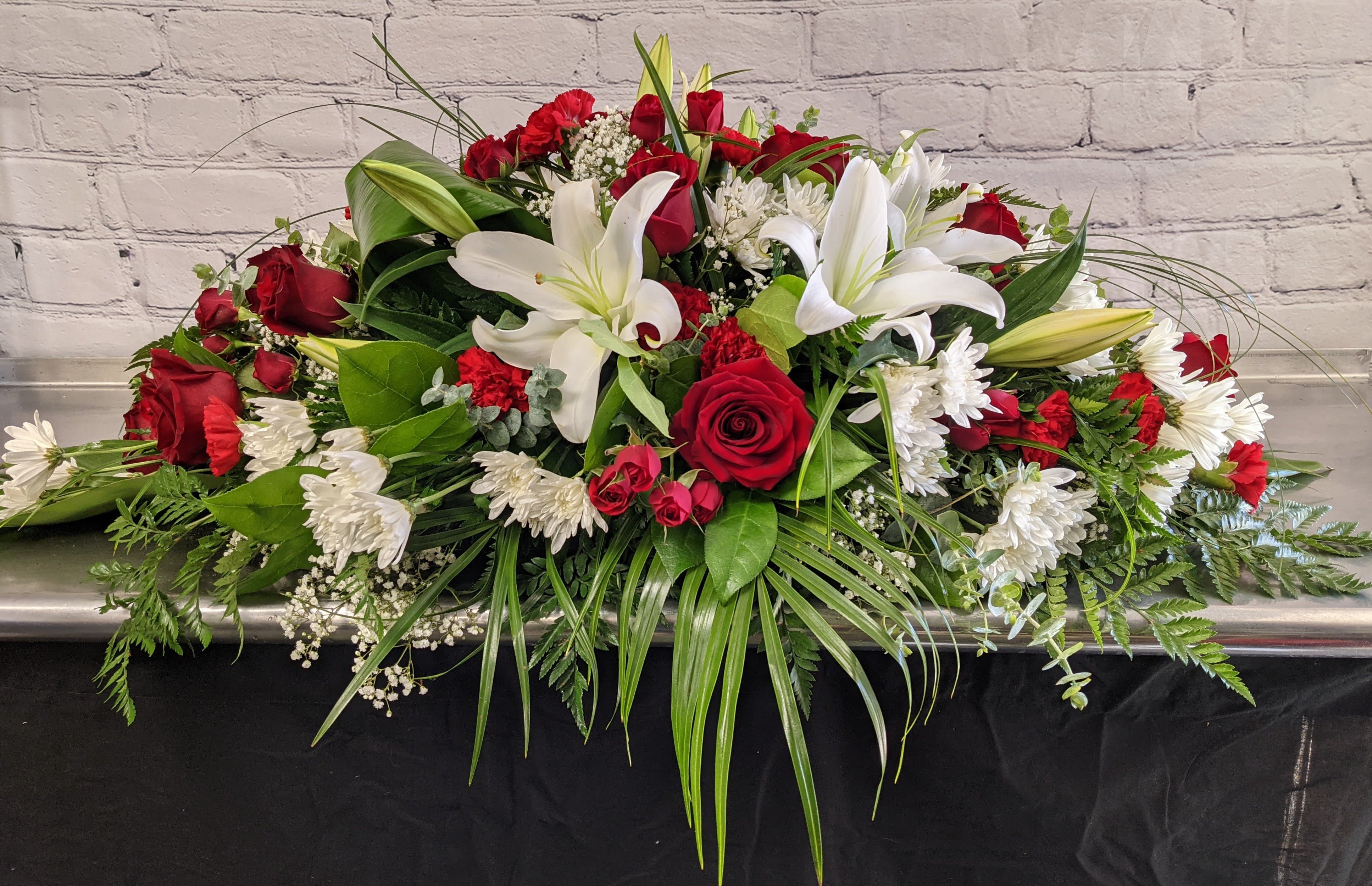 Casket spray with red roses, white lilies, and white chrysanthemums