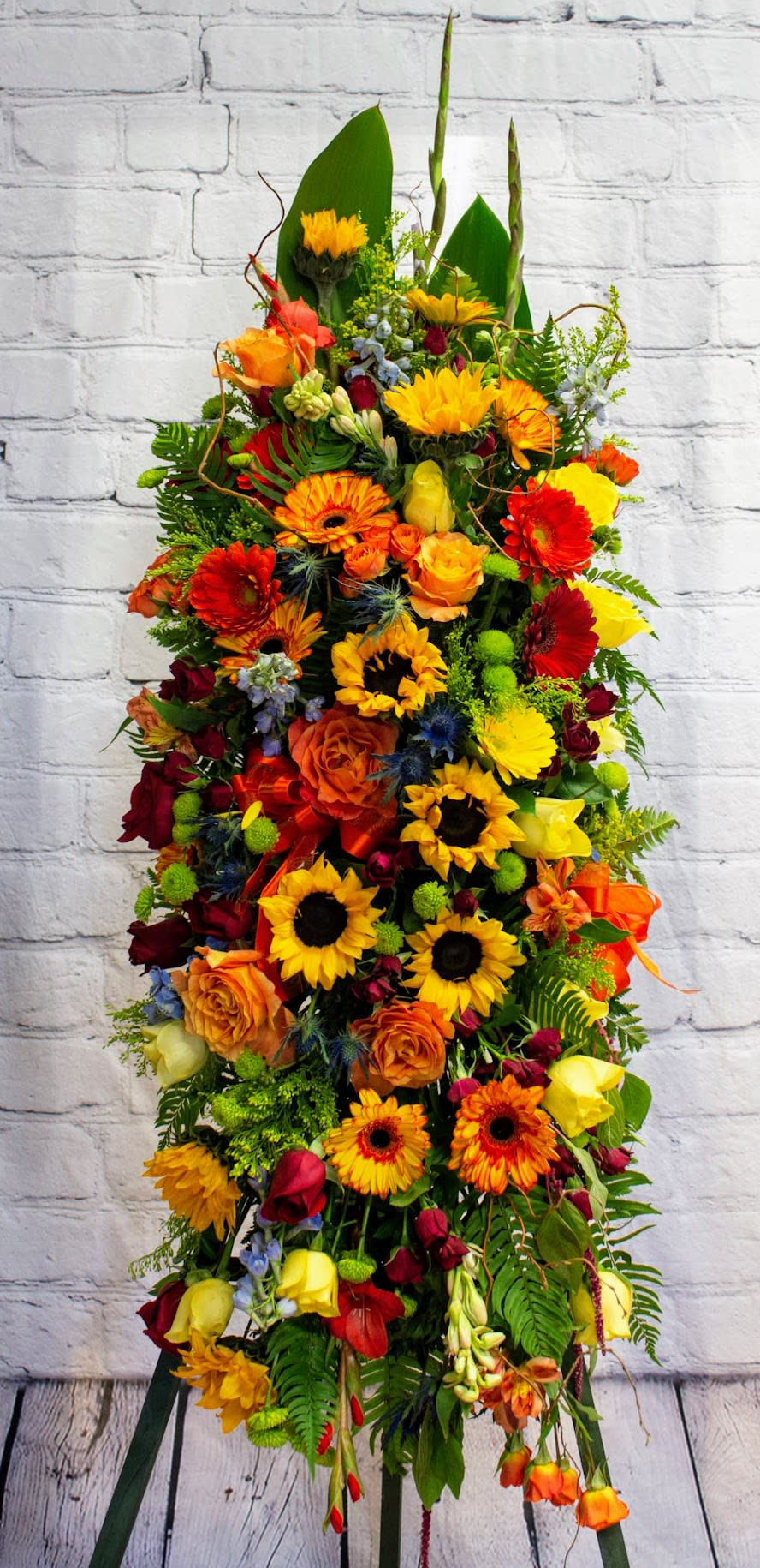 Tall arrangement of sunflowers, roses, and gerbera daisies in bright mixed colors