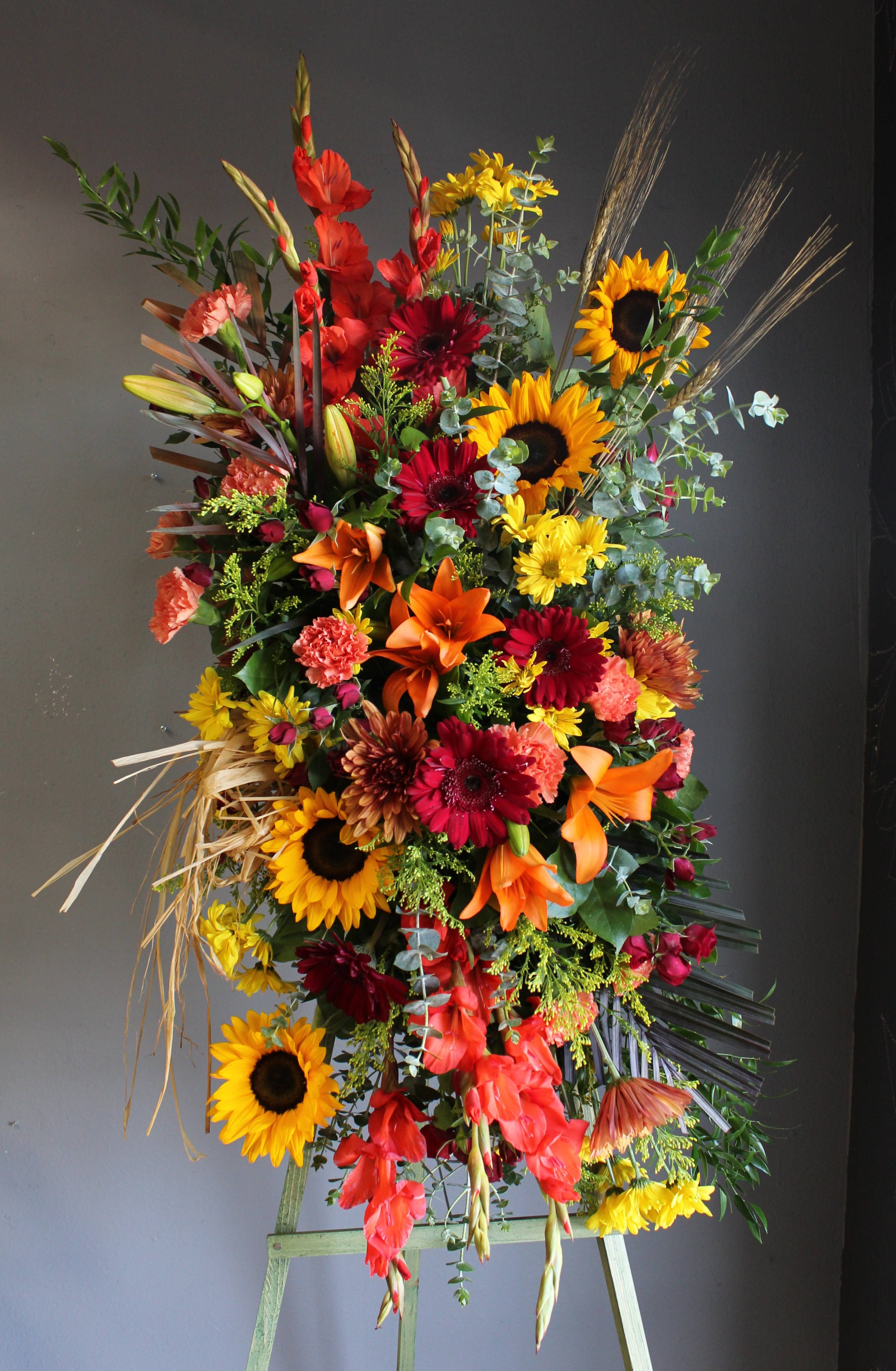 Tall floral spray with sunflowers, lilies, and red gerbera daisies