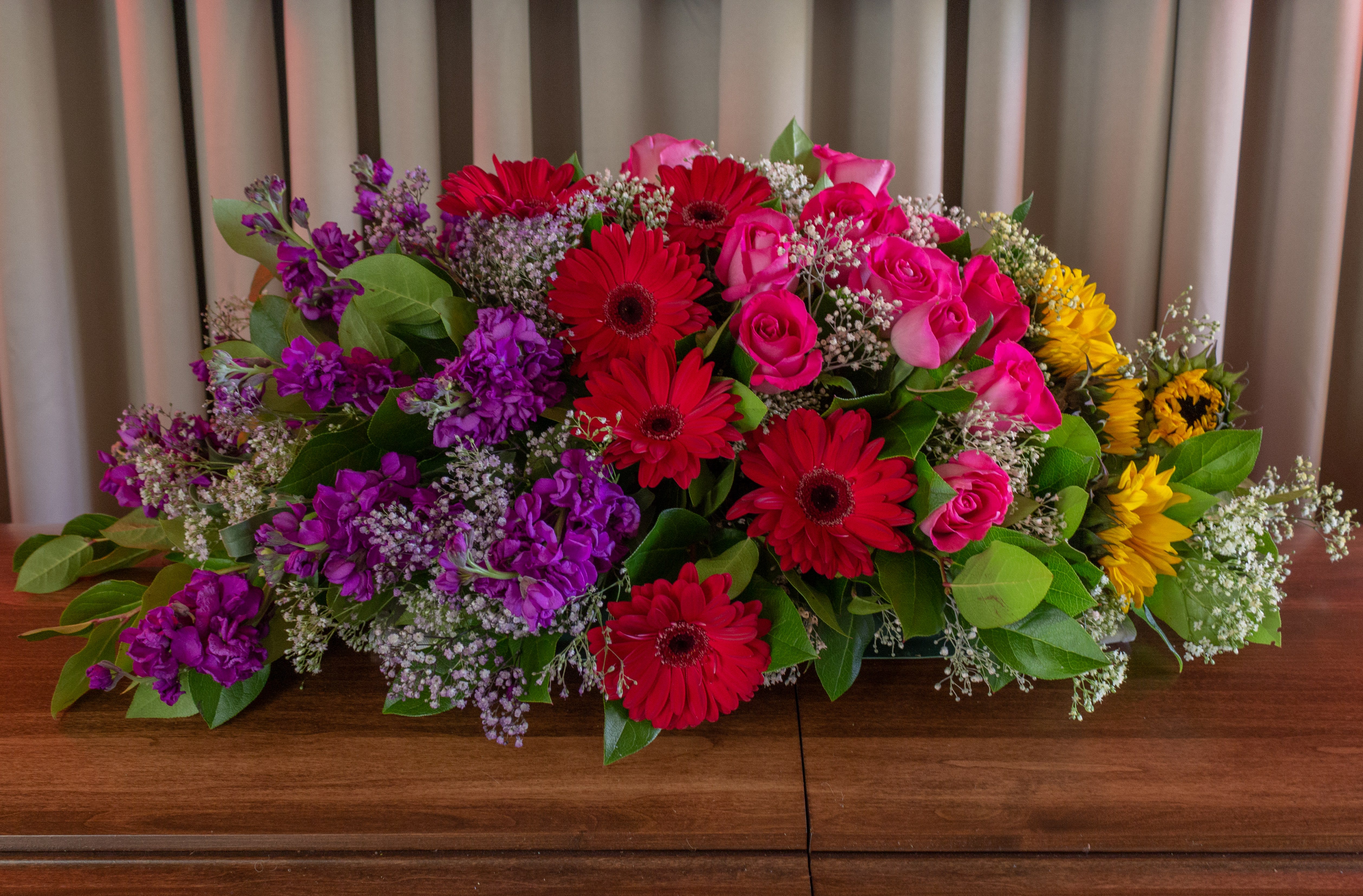 Large mixed bouquet with red gerberas, pink roses, purple flowers, and yellow sunflowers