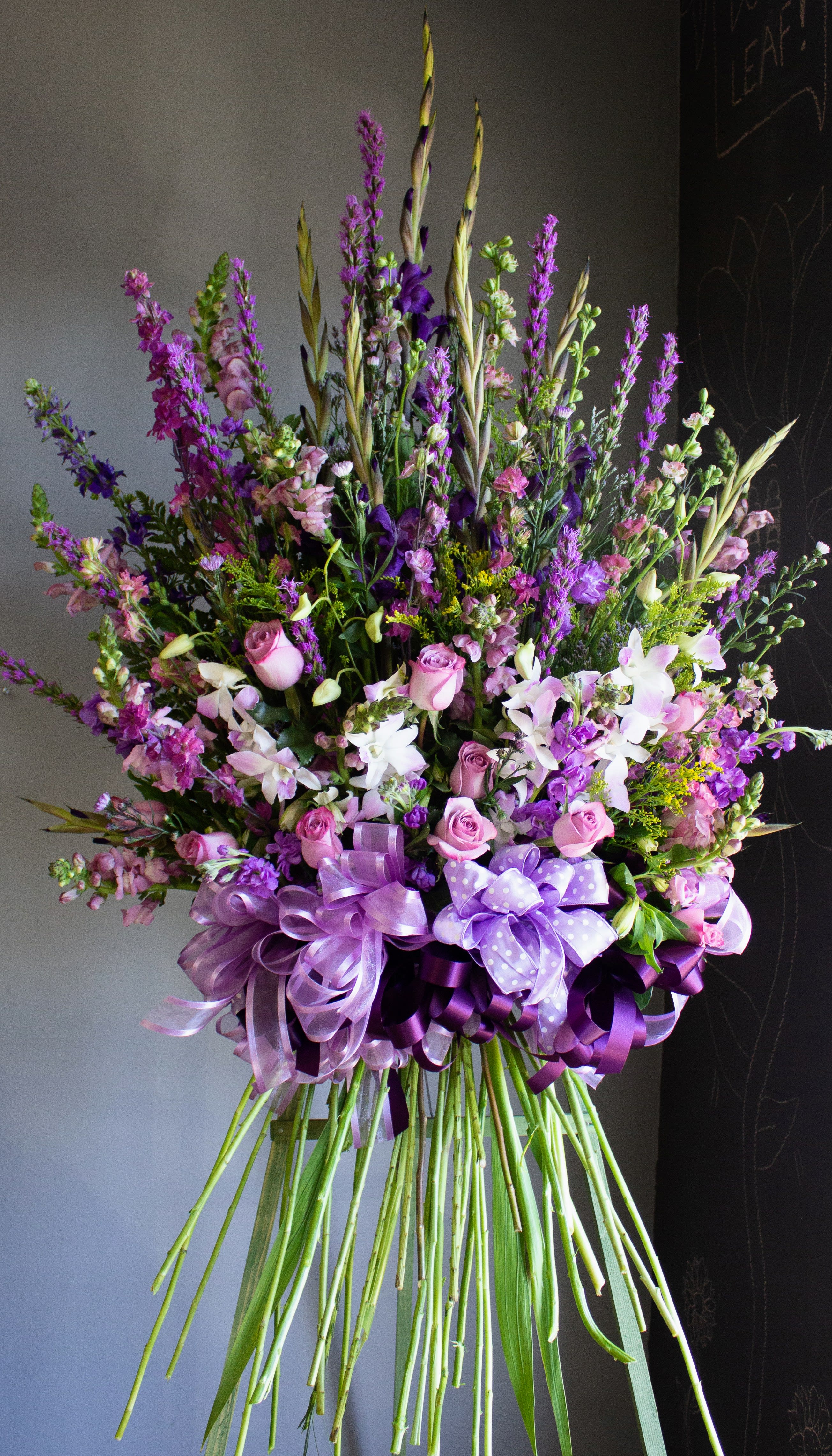 Tall bouquet of pink and purple flowers with ribbon bows