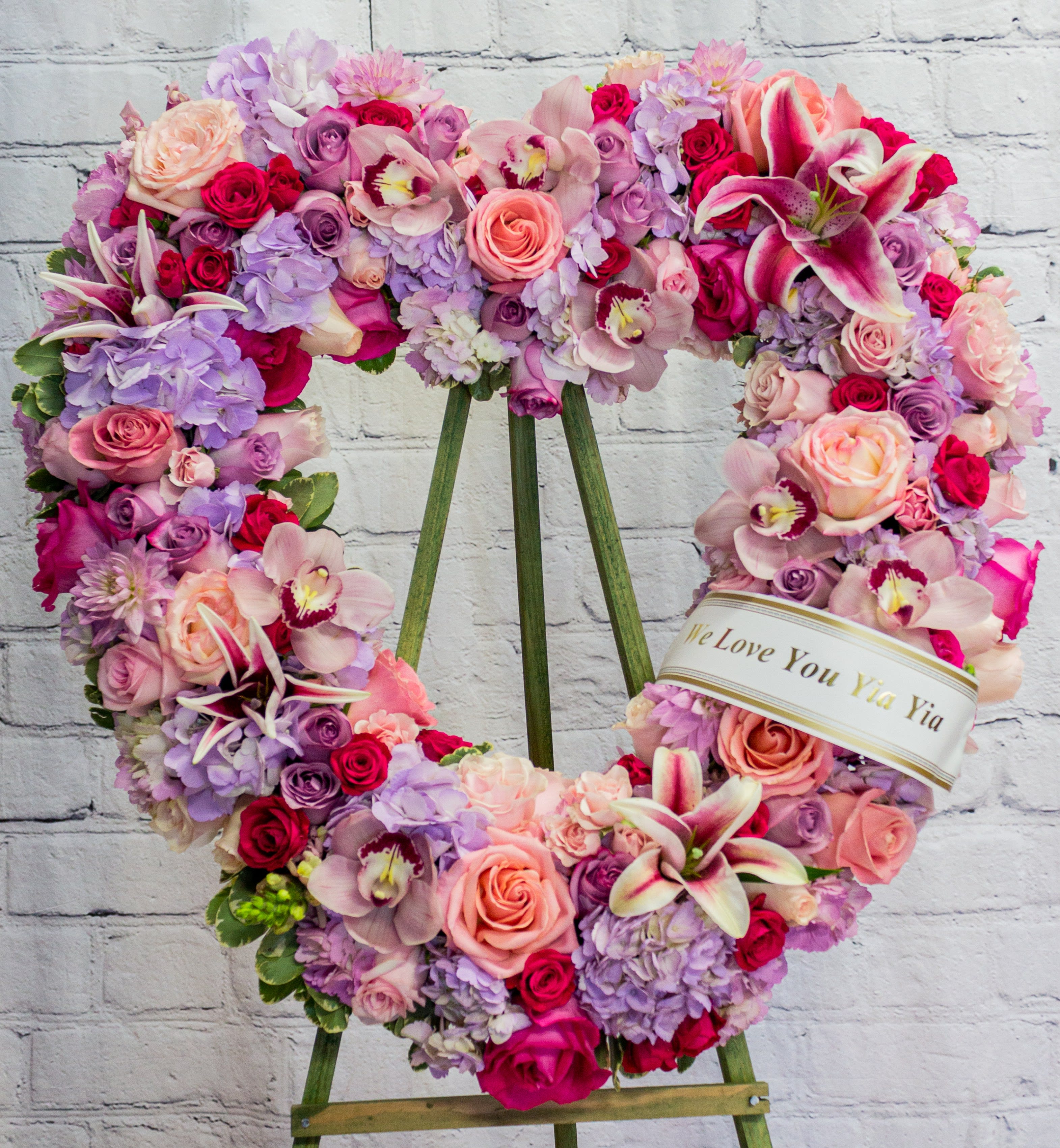 Heart-shaped floral wreath on an easel with pink, purple, and white blooms