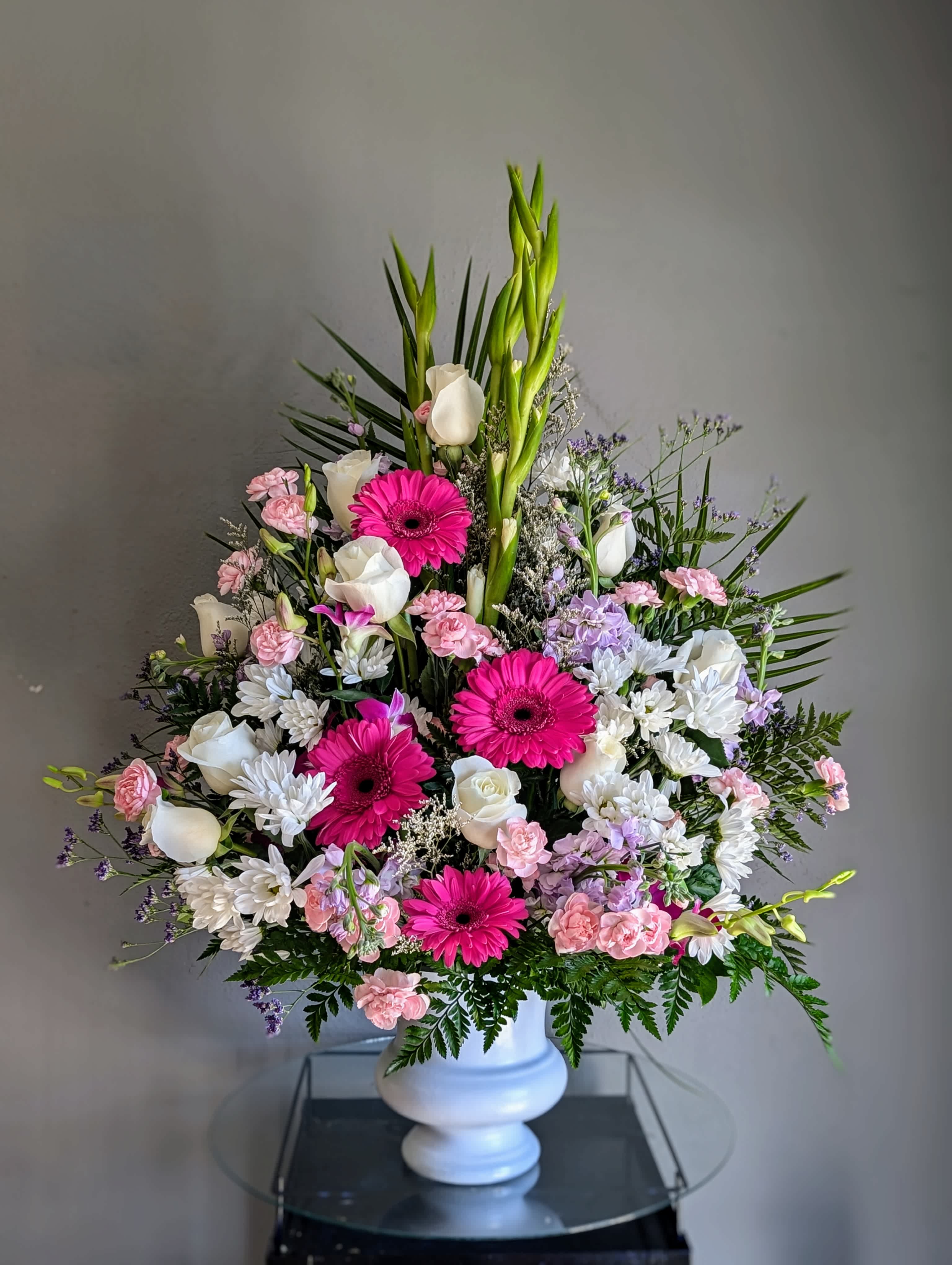 Tall mixed floral arrangement in a white vase with pink and white blooms
