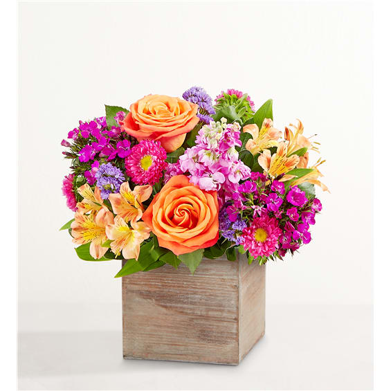 Bright mixed bouquet in a wooden box with orange roses and pink flowers