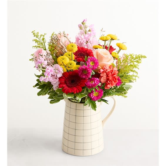Mixed bouquet of colorful flowers in a cream checkered pitcher