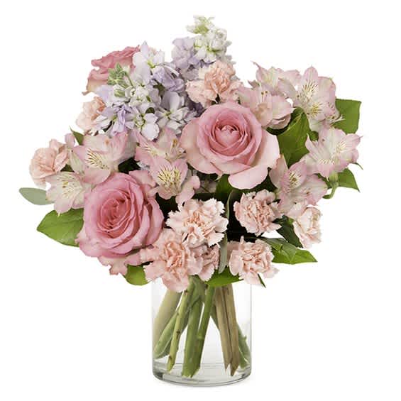 Pink roses and pastel flowers arranged in a clear glass vase