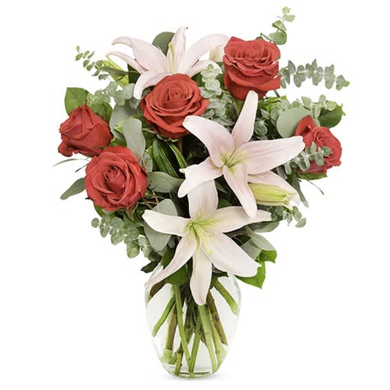Pink roses and white lilies in a clear glass vase