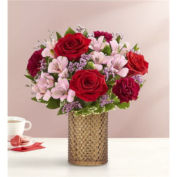 Bouquet of red roses and pink flowers in a textured vase