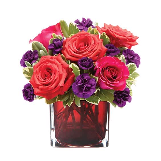 Pink and red roses with purple carnations in a red glass vase