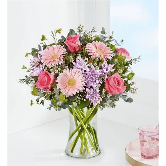 Pink roses and daisies arranged in a clear glass vase