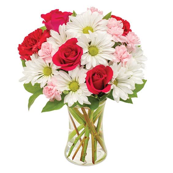 Bouquet of red roses, white daisies, and pink carnations in a glass vase