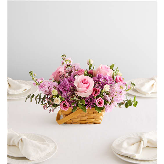 Pink and purple flower arrangement in a woven basket on a table