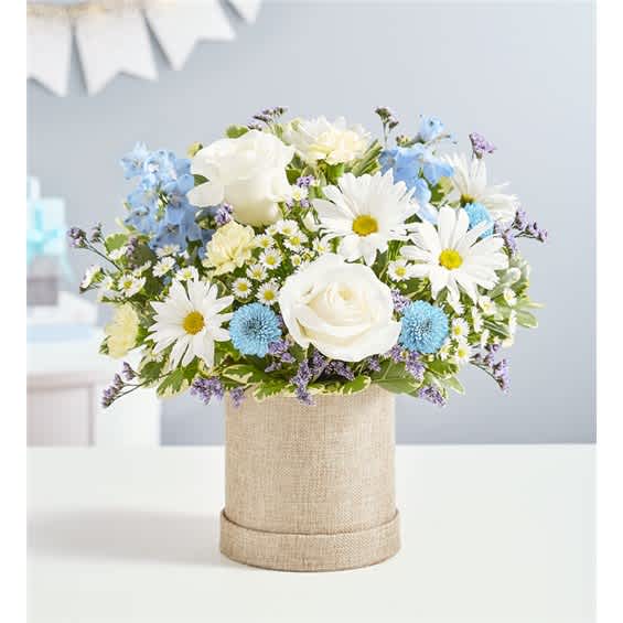 White roses and daisies in a burlap-covered cylinder vase