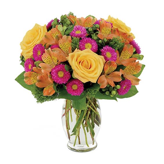 Bouquet of yellow roses, orange alstroemeria, and magenta daisies in a glass vase