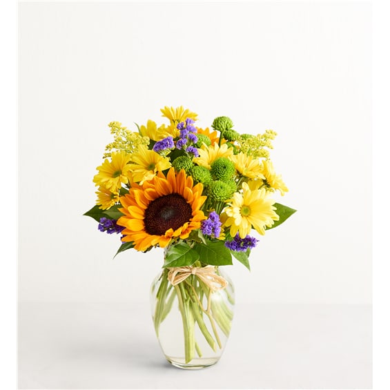 Sunflower and yellow daisy bouquet in a clear glass vase
