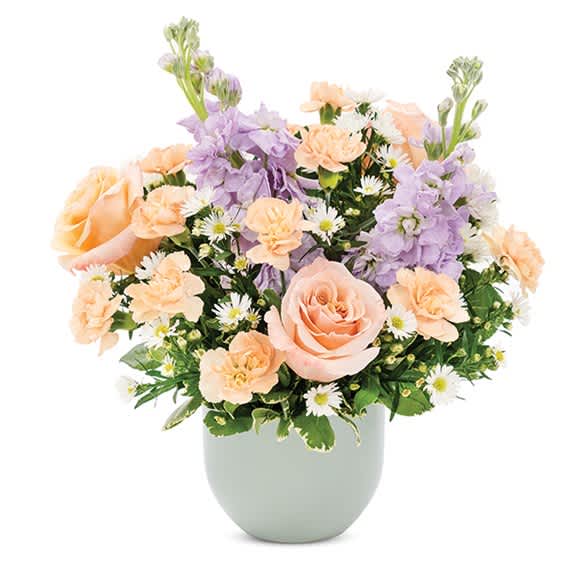Peach and lavender flower arrangement in a pale vase