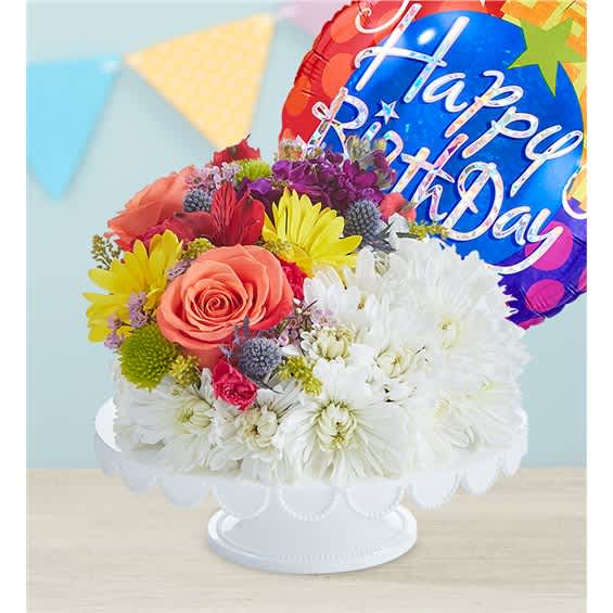 Colorful birthday bouquet in a white pedestal bowl with a foil balloon
