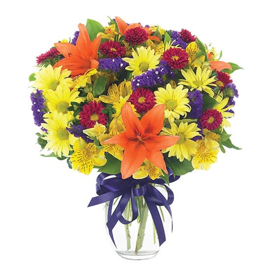 Bouquet of yellow daisies, purple flowers, and orange lilies in a glass vase