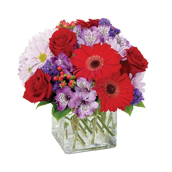 Bouquet of red roses and gerbera daisies in a clear glass vase