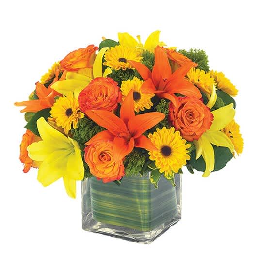 Orange and yellow flowers arranged in a square glass vase