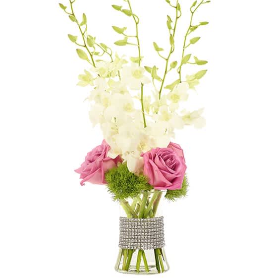Pink roses and white orchids in a clear vase with a rhinestone wrap