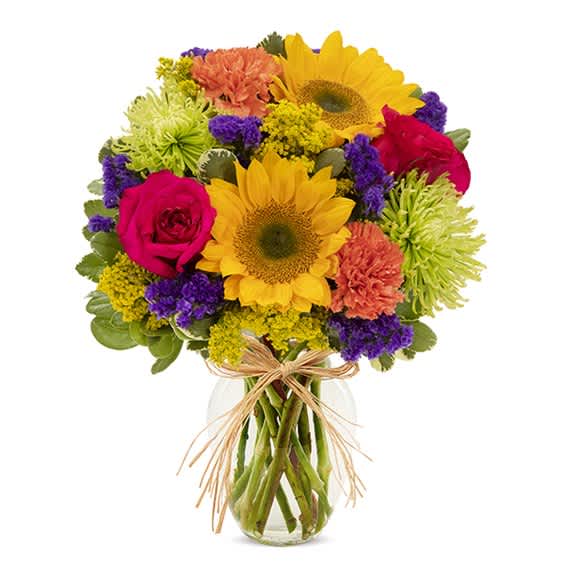 Mixed bouquet of sunflowers, roses, and carnations in a glass vase