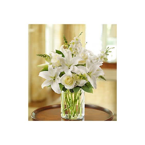 White lilies and roses arranged in a clear glass vase