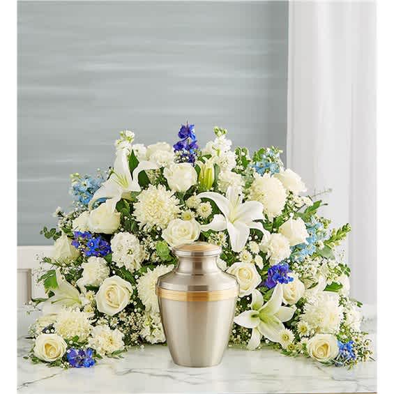 White floral funeral arrangement with a silver urn in front