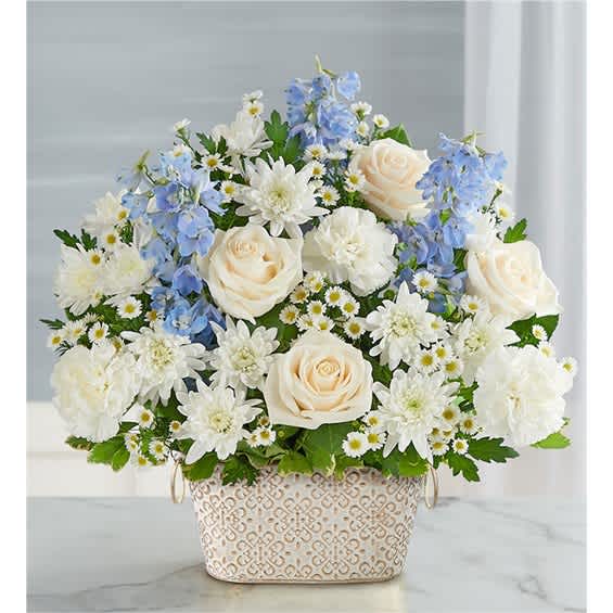 White roses and blue flowers arranged in a patterned basket