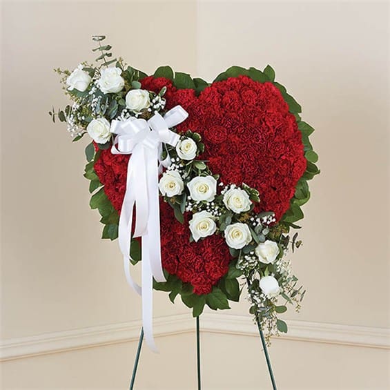 Heart-shaped red floral standing arrangement with white roses and a white ribbon