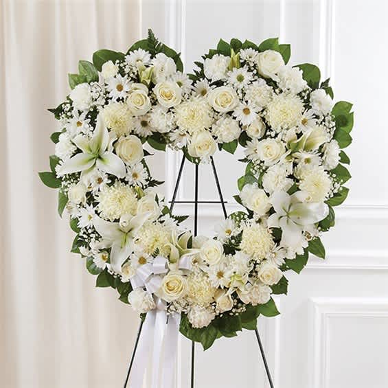 Heart-shaped white floral wreath on a stand with a ribbon