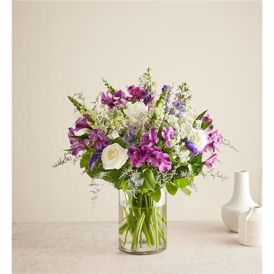 Mixed bouquet of purple and white flowers in a clear glass vase