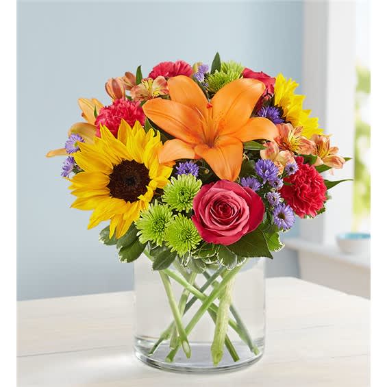 Mixed bouquet with sunflower, orange lily, pink rose, and a clear glass vase