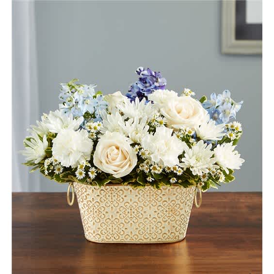White and pale blue flowers arranged in a patterned metal basket