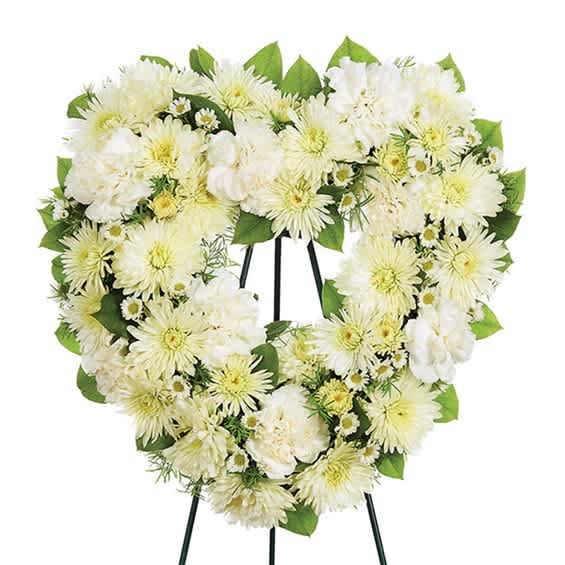 Heart-shaped white floral wreath on a stand