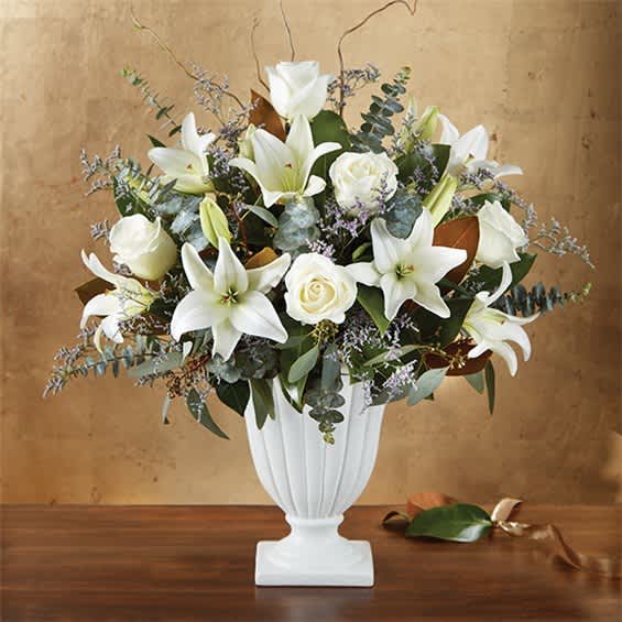 White lilies and roses arranged in a white pedestal vase