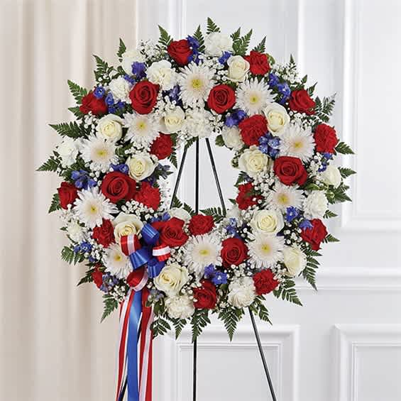 Circular standing wreath of red and white roses with white daisies and blue accents